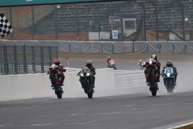 雨のなかウィリーをしチェッカーを受けるライダーたち