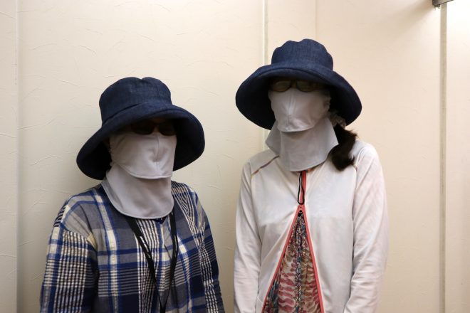 UVカットマスク、紫外線100％カットの帽子、指先ギリギリまでのラッシュガードで肌という肌を隠す女性の二人連れ。「UVカットマスクは3年前から使っています。化粧崩もなしで、完璧に日焼けしません」