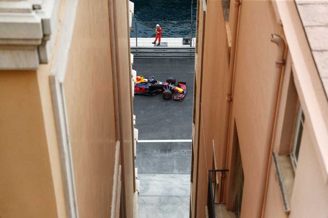 F1モナコGPを走るマックス・フェルスタッペン。ビル越しにマシンと海が見えるカット