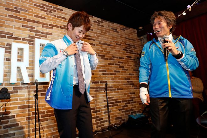 プロ野球の入団会見さながらに、Team KAGAYAMAブルーのシャツにそでを通す長谷川聖