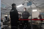 訪問者エリアのビニールカーテン越しに話す土屋武士監督