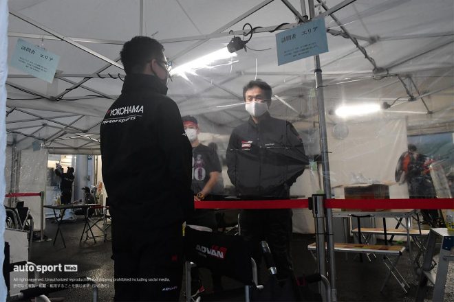 訪問者エリアのビニールカーテン越しに話す土屋武士監督