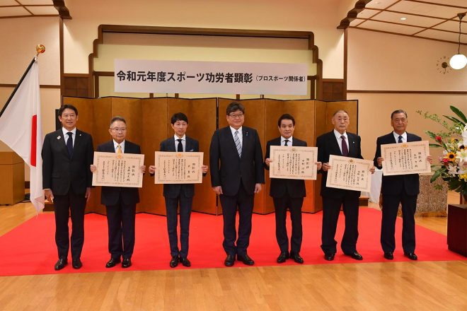 萩生田光一文部科学大臣、鈴木大地スポーツ庁長官、5名の顕彰者とともに記念写真に収まる高橋国光総監督