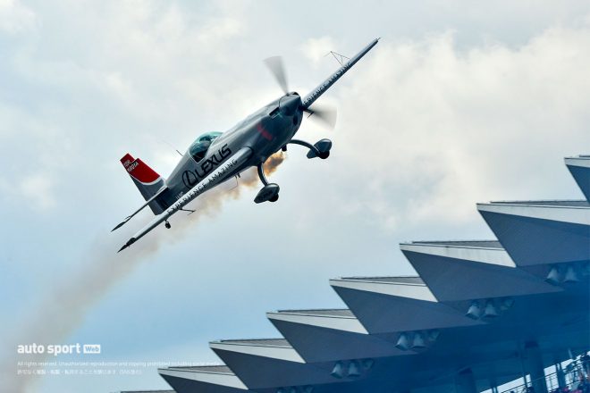 富士スピードウェイのメインストレート上をフライトする室屋義秀のエクストラ330SC