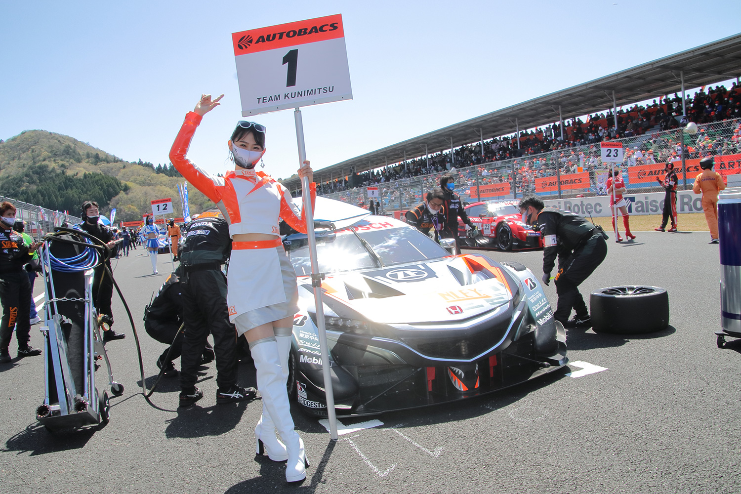 チャンピオンの証であるカーナンバー1のグリッドボードを持つSTANLEYレースクイーンの相沢菜々子さん