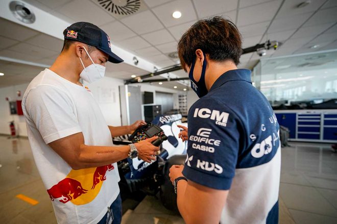 F1マシンのステアリングを握る中上貴晶と、説明する角田裕毅