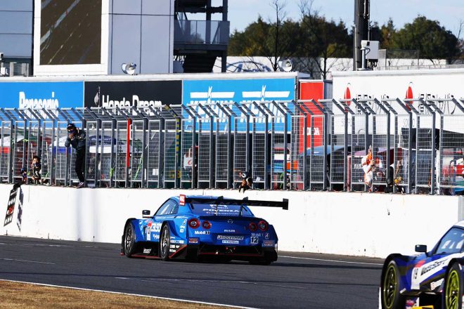 チェッカー目前、スローダウンする12号車の背後に迫る19号車宮田莉朋。その様子をピットウォールに立ち見守るのは坂東マサ監督だ。