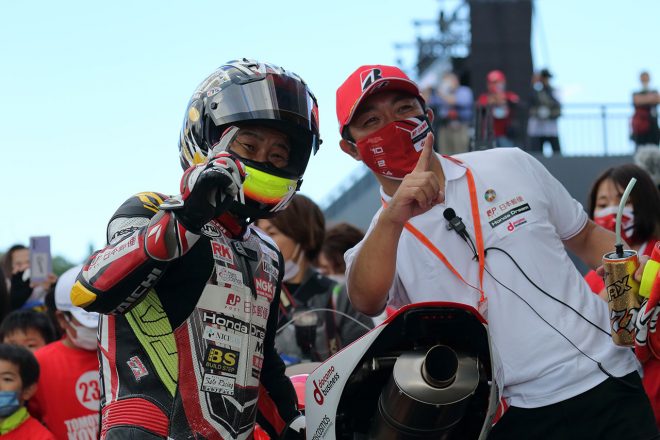 レース1のパルクフェルメにて小山知良選手（左）と手島雄介監督（右）。ふたりそろって勝利のポーズ