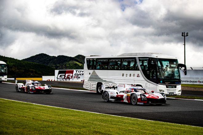 サーキットサファリで観光バスの脇を追い抜いていくトヨタGR010ハイブリッド　2022年WEC第5戦富士6時間