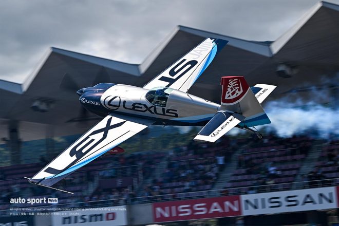 手を振りながら富士スピードウェイのストレート上をフライトする室屋義秀